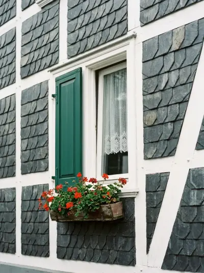 Fachwerkfassade mit Schieferschindeln und grünen Fensterläden